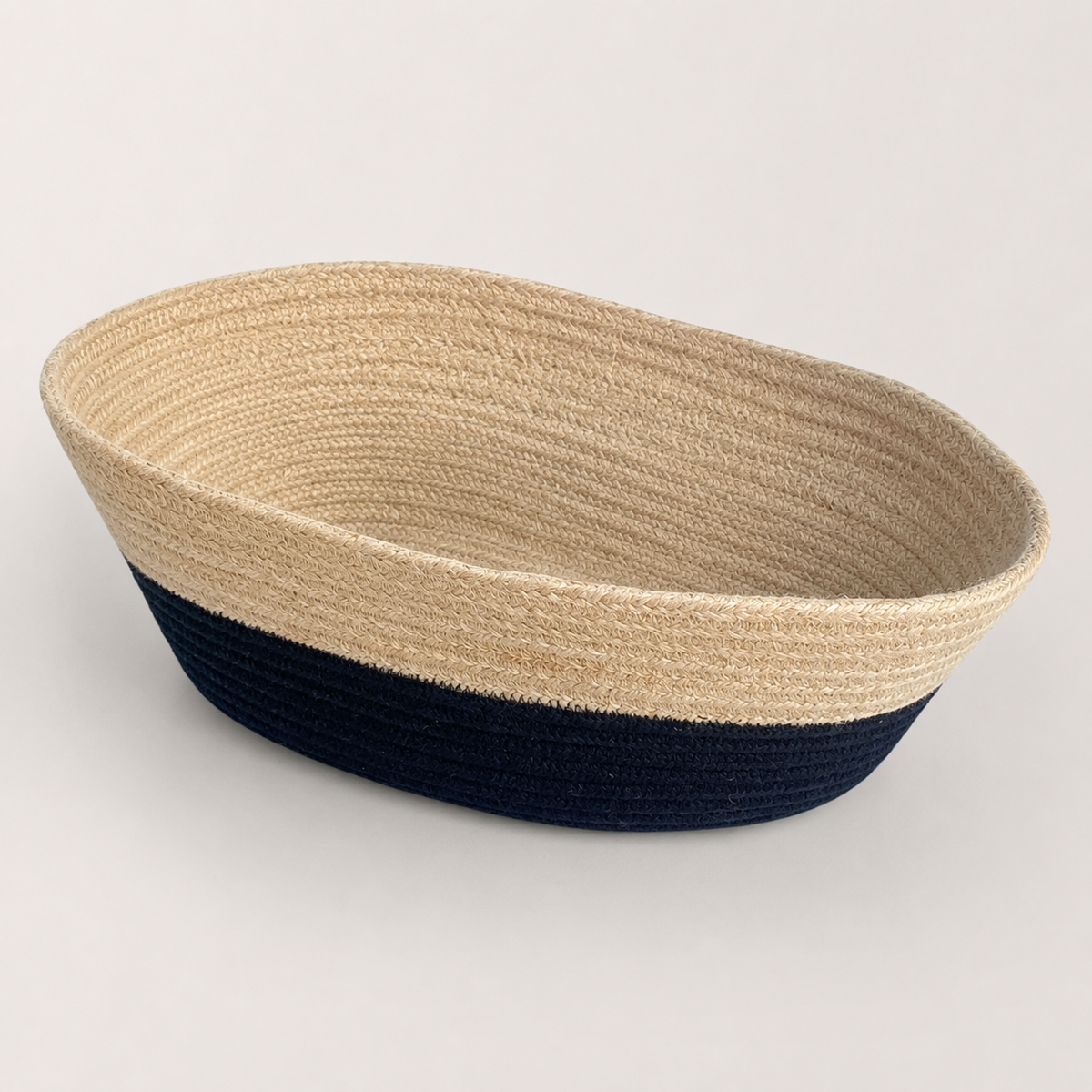 Angled view of boat-shaped beige and black cotton cord fruit basket